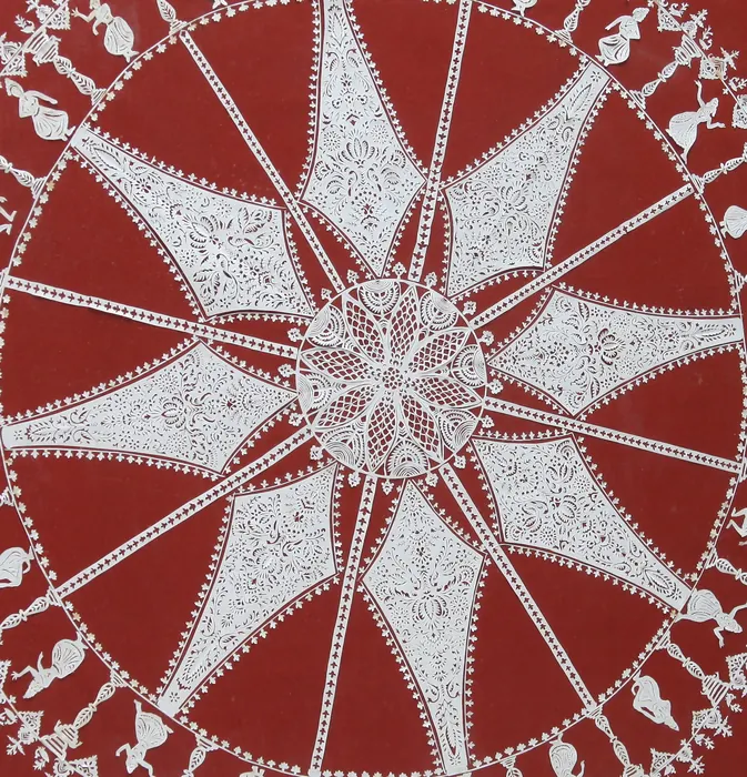 Close-up of a white paper-cut wheel pattern on red