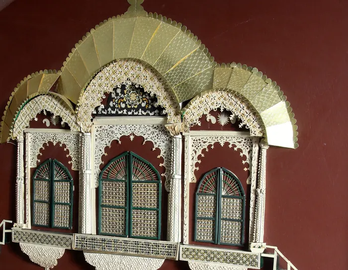 Close-up of a cream paper jharokha with lattice windows and a staircase