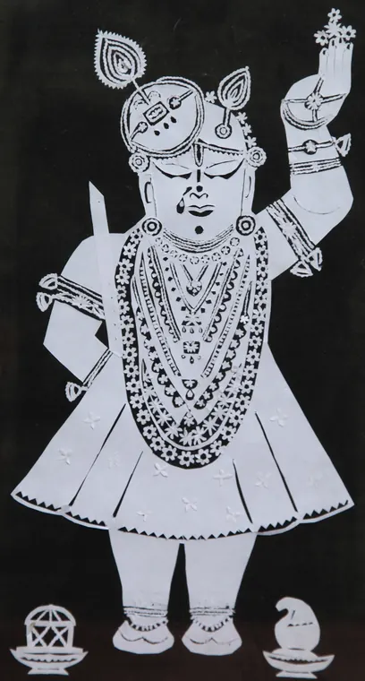 Shrinathji in White: the deity in full shringar, cut from white paper on black
